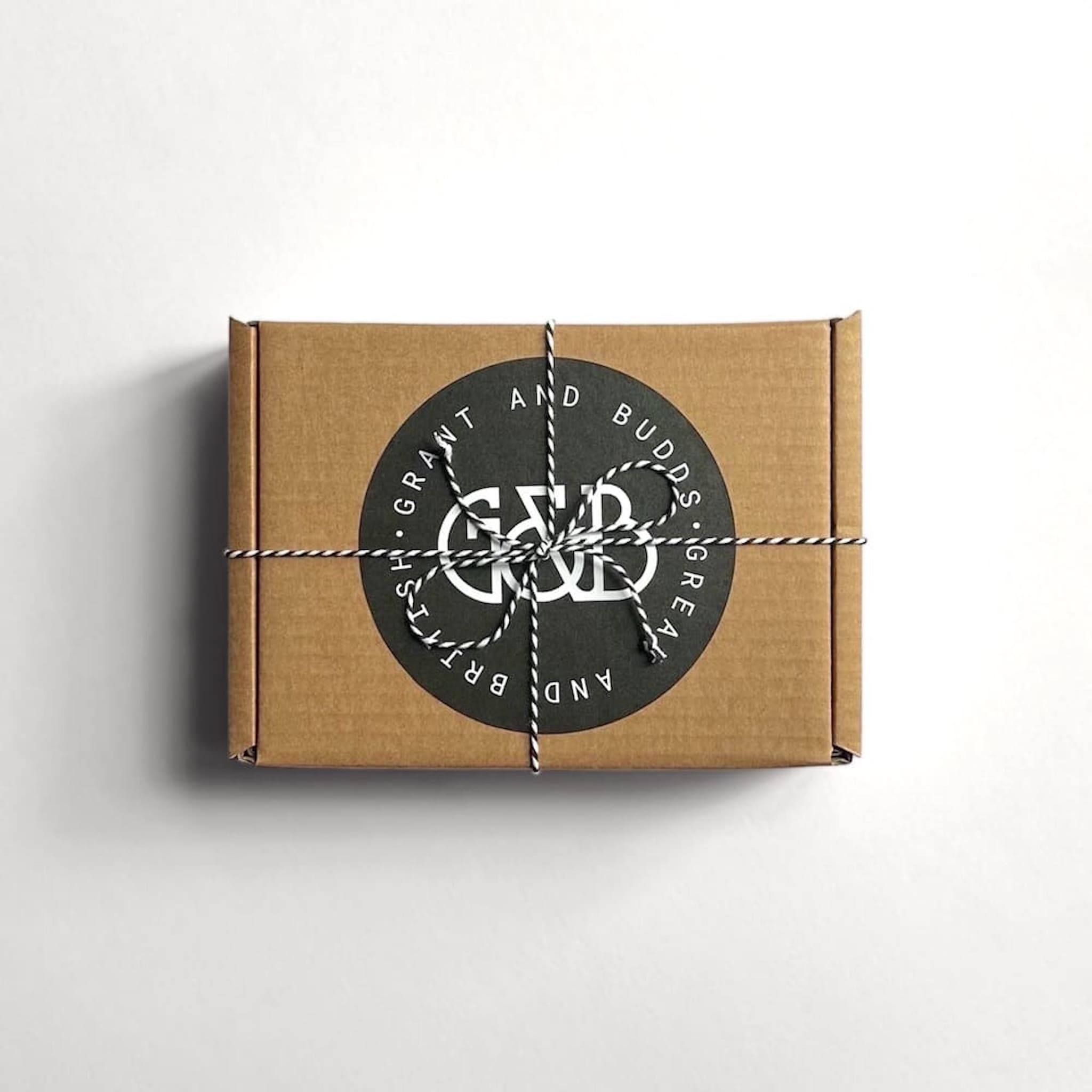Grant and Budds brown gift box with a black label tied with string on a white background