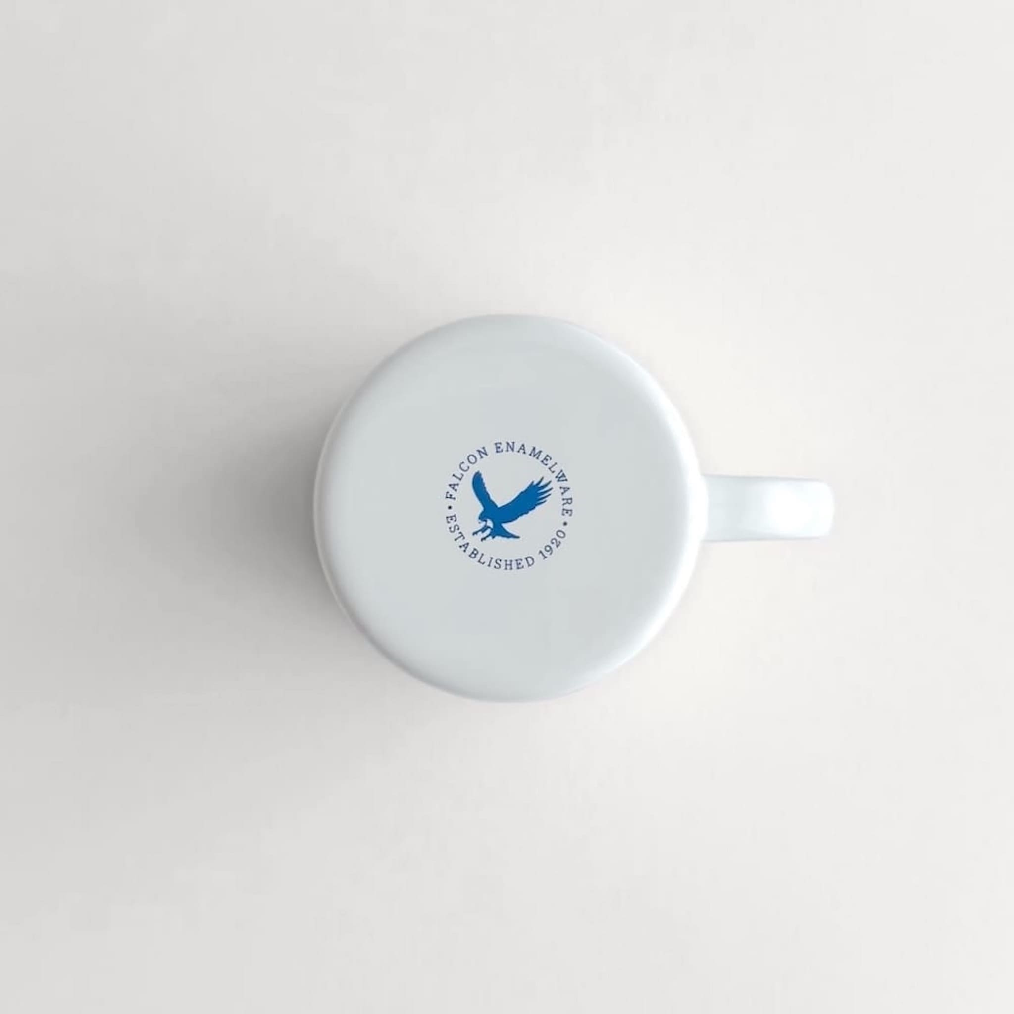 Underside view of a white Falcon enamelware mug with authenticity logo stamp