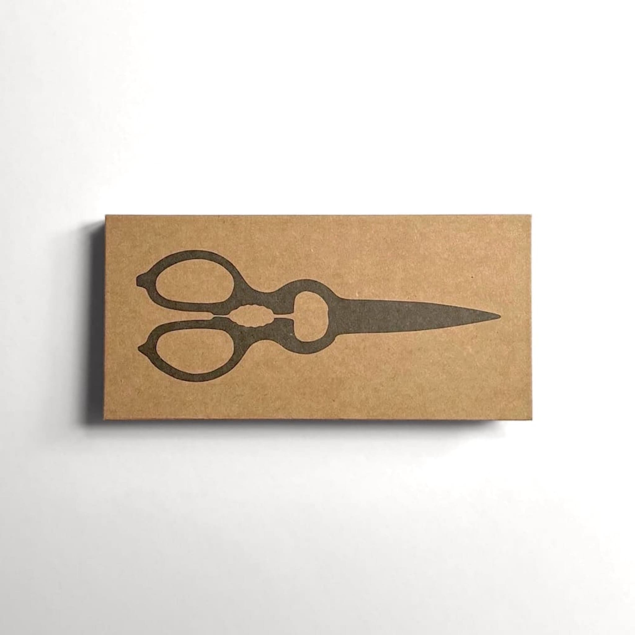 Kraft paper box with a black silhouette of scissors on a white background