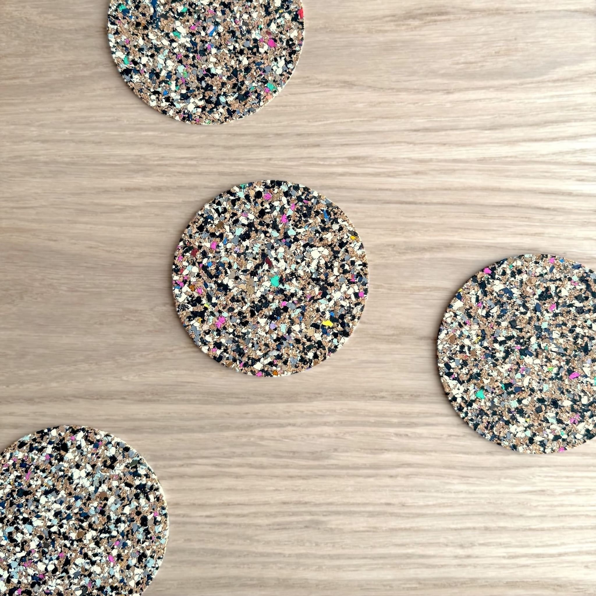 Four round speckled coasters on a wooden surface