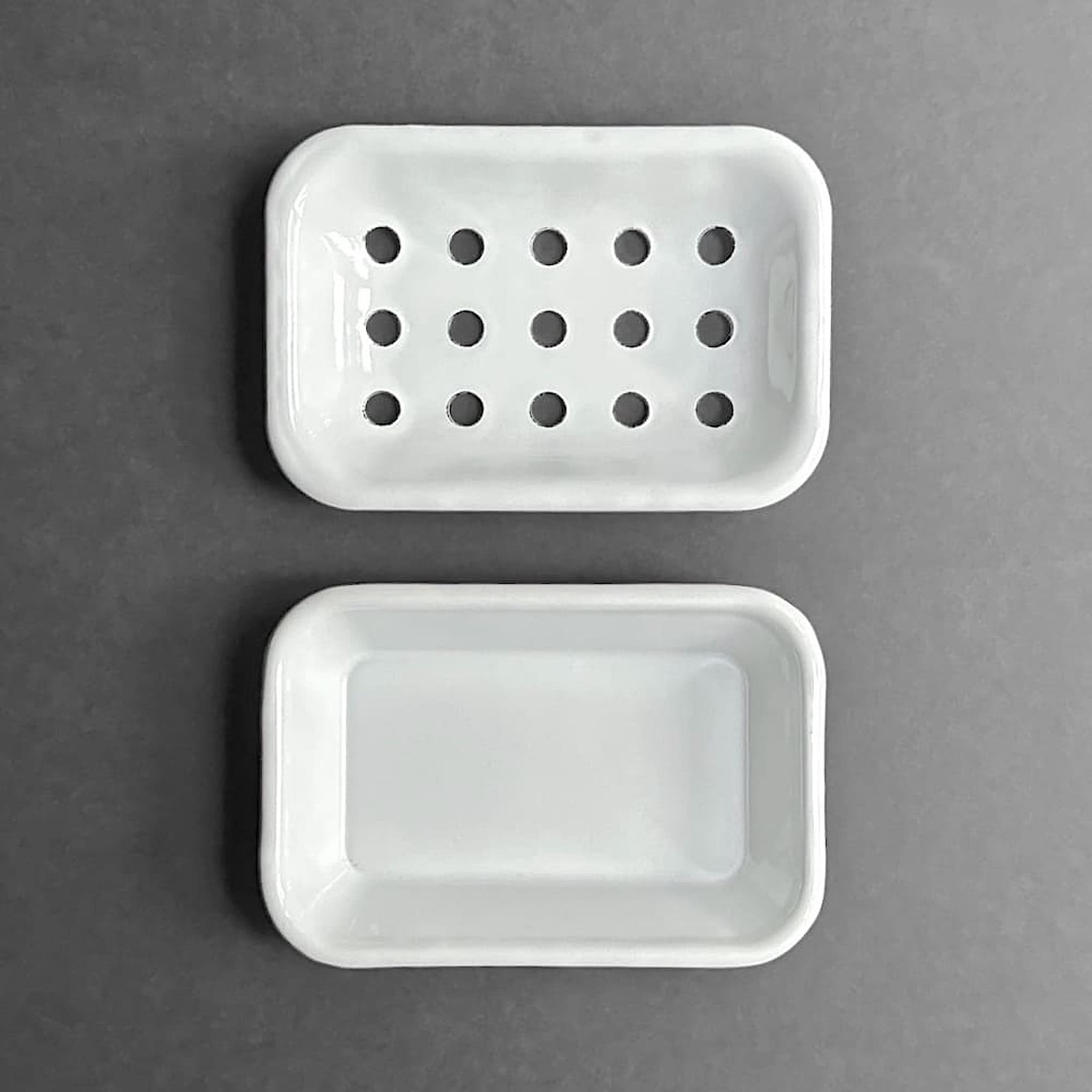 Above view of white enamel soap dish and drainage tray on a grey background