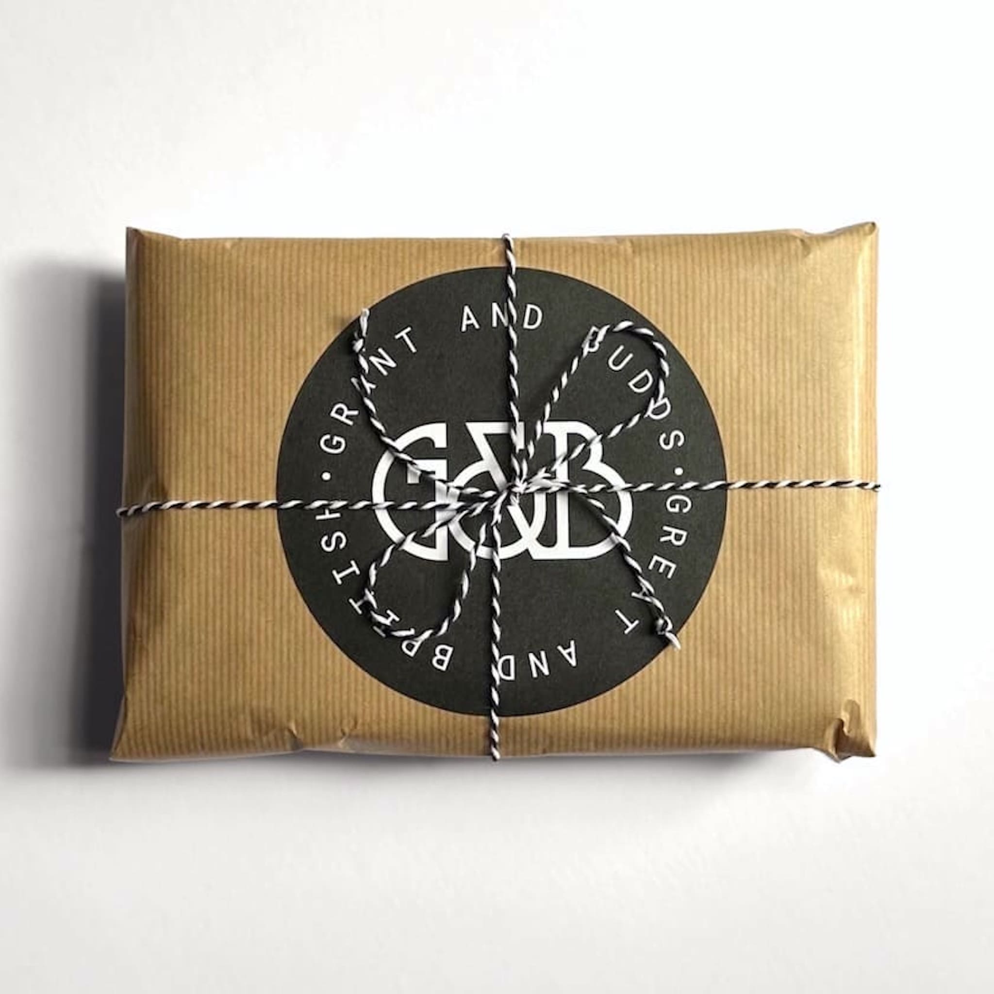 Grant & Budds gift packaged kitchen utensils wrapped in brown paper with a black label on a white background