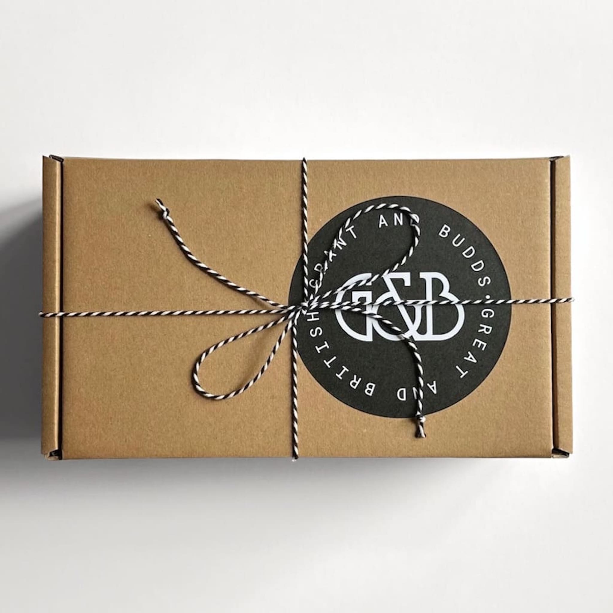 Grant and Budds gift box with a black round label tied with string on a white background