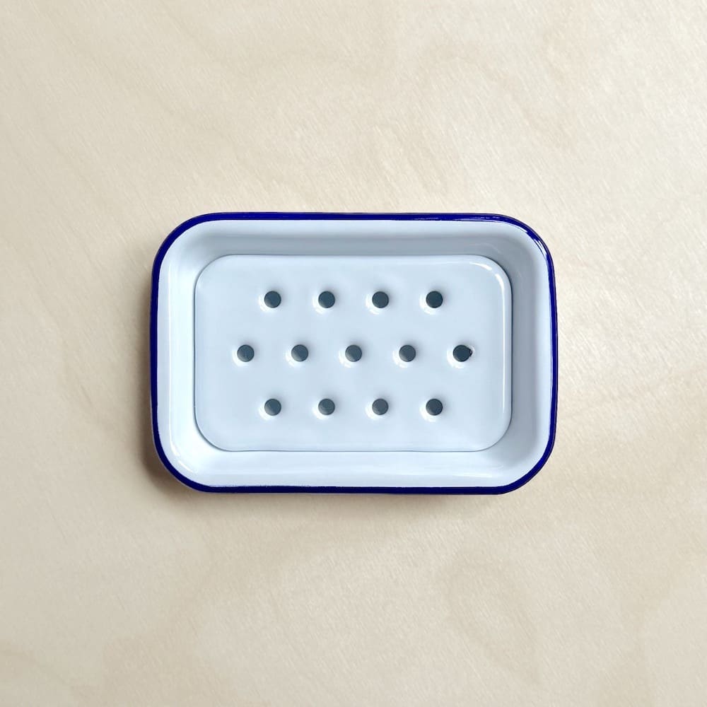 Above view of a white Falcon enamelware soap dish with a blue rim