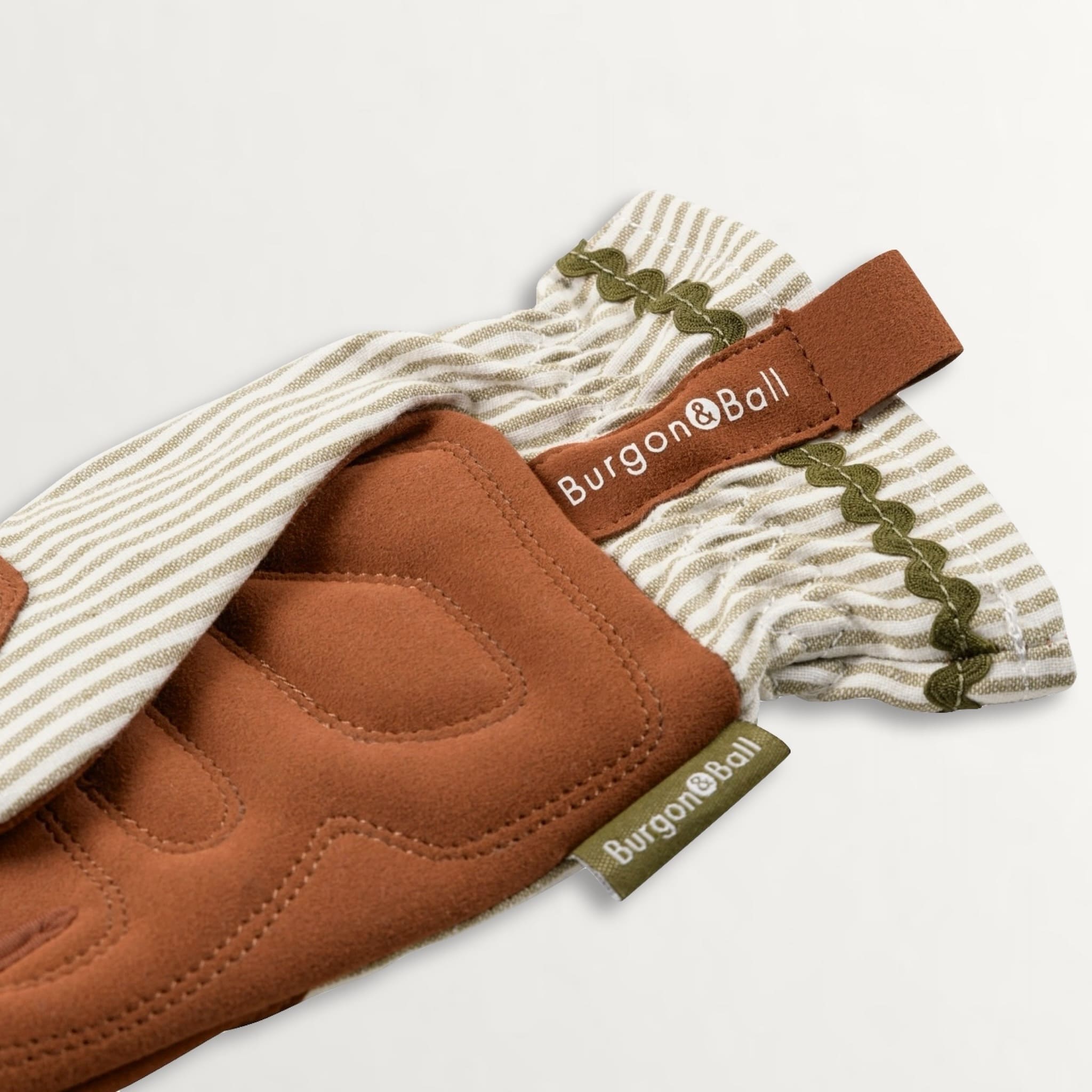 Close up showing quilted palms of gardening gloves in brown faux suede, green striped backing and a ric rac trim to the wrist.