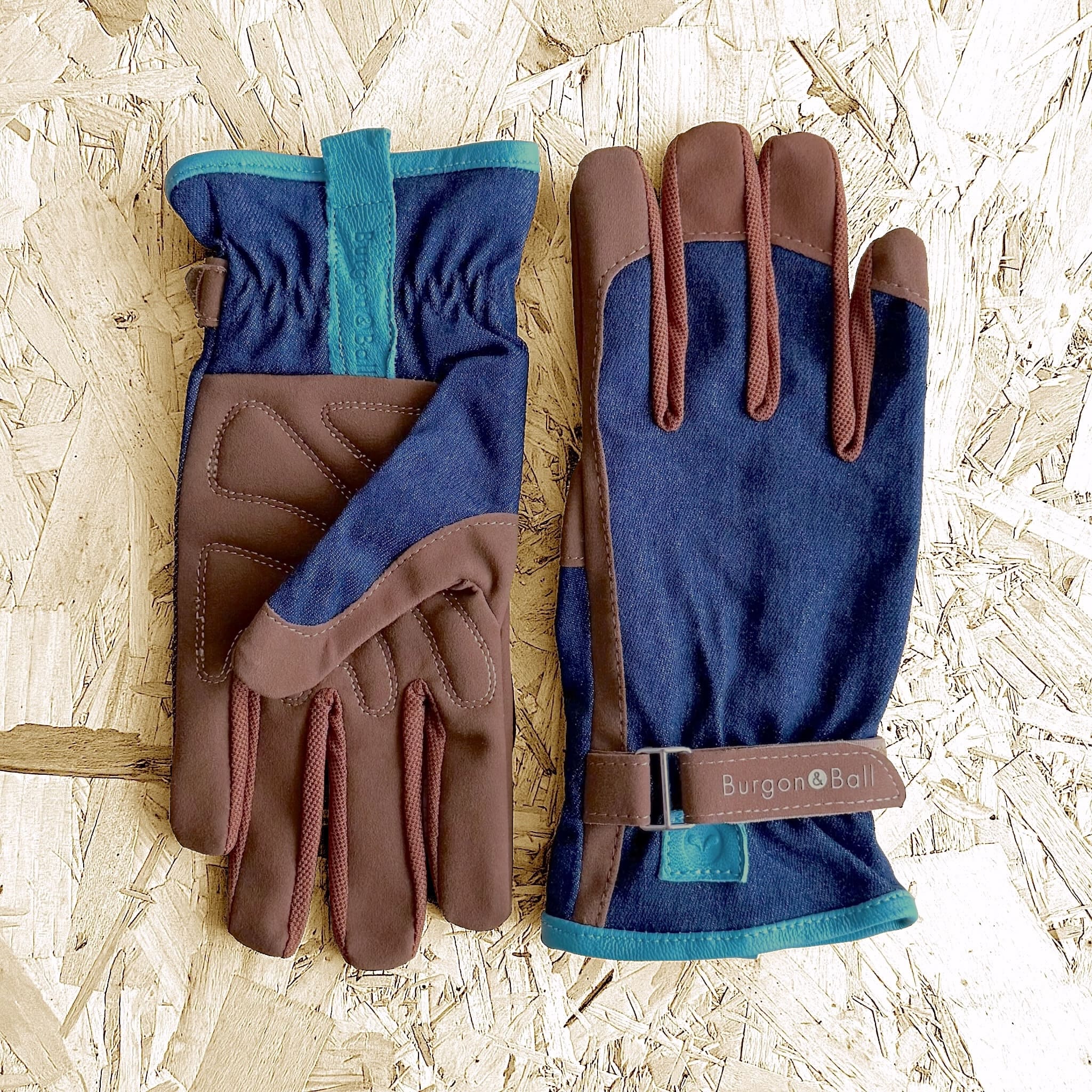 Pair of blue and brown gloves with a visible brand logo on a wooden background
