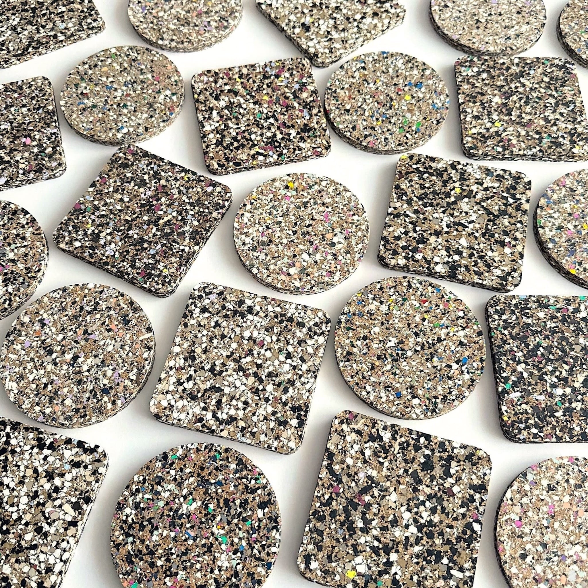 Collection of square and round speckled coasters on a white background