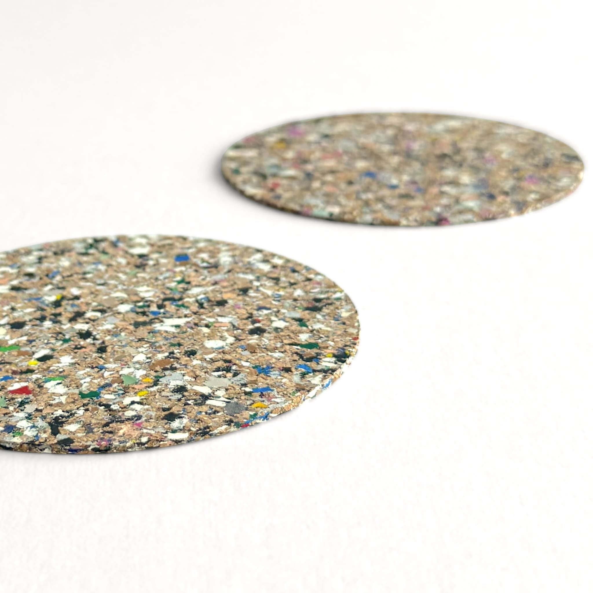 Two round, multicoloured coasters on a white background