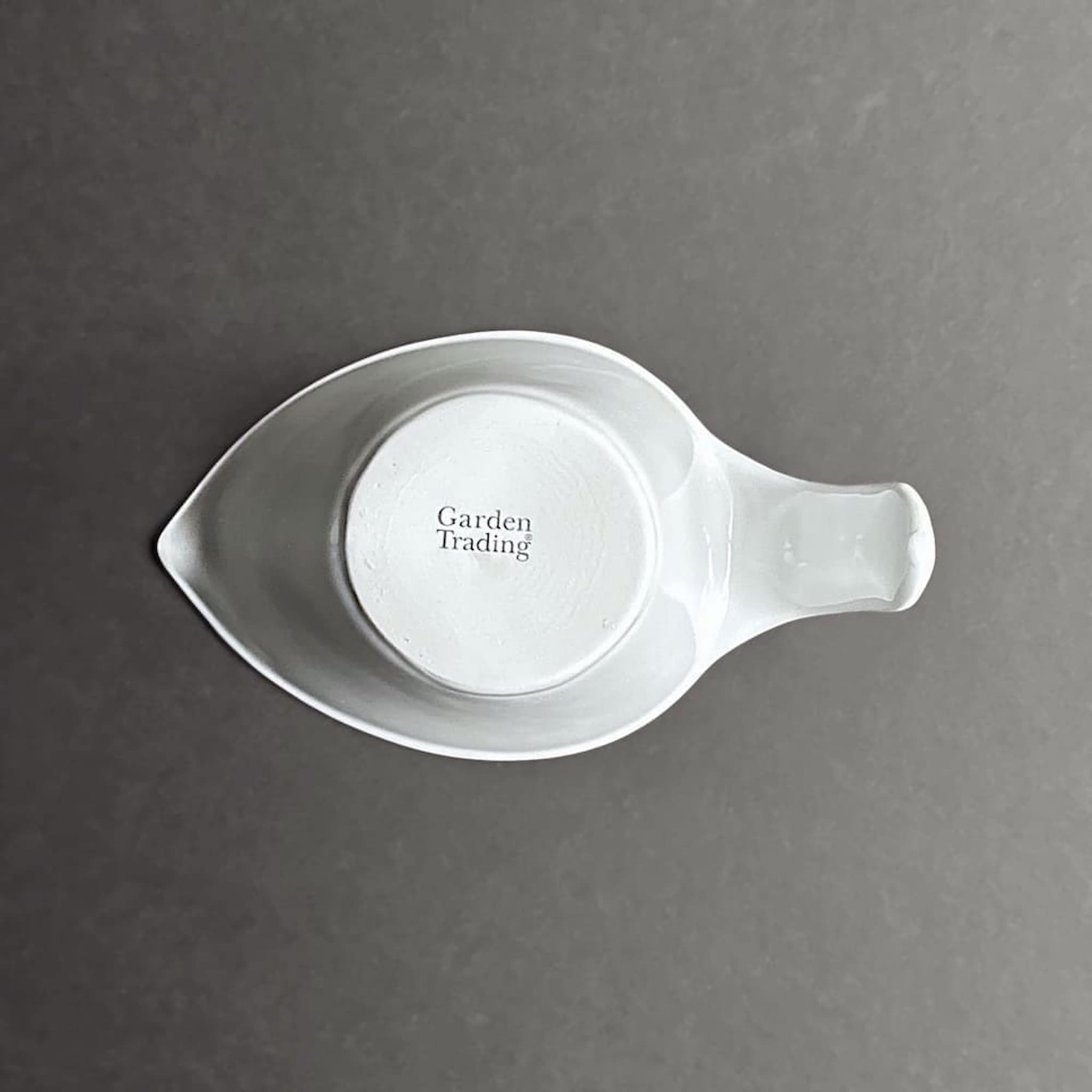 Base view of white ceramic jug shaped measuring cup with 'Garden Trading' branded stamp on a grey background