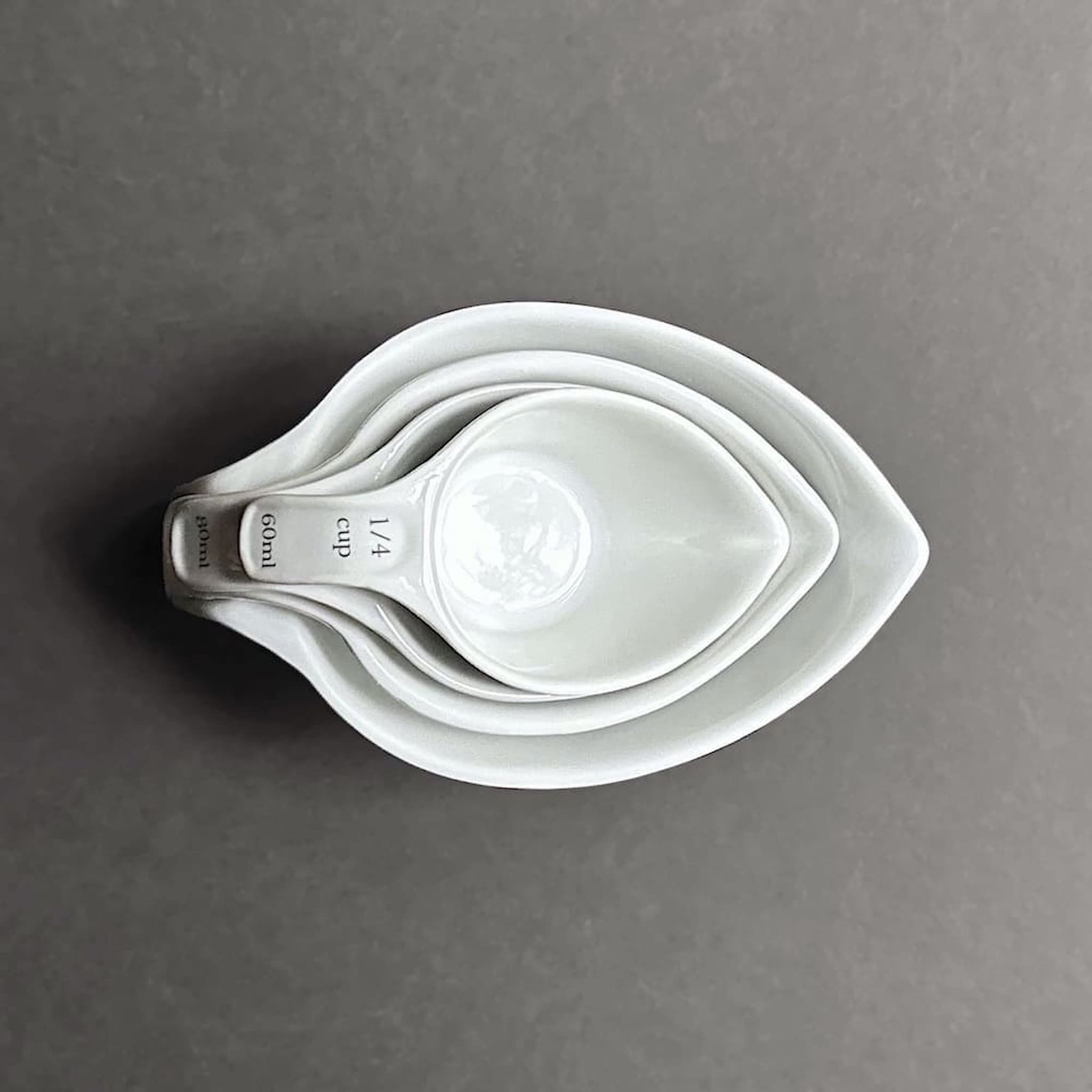 Above view of a set of white measuring cups stacked on a dark grey background