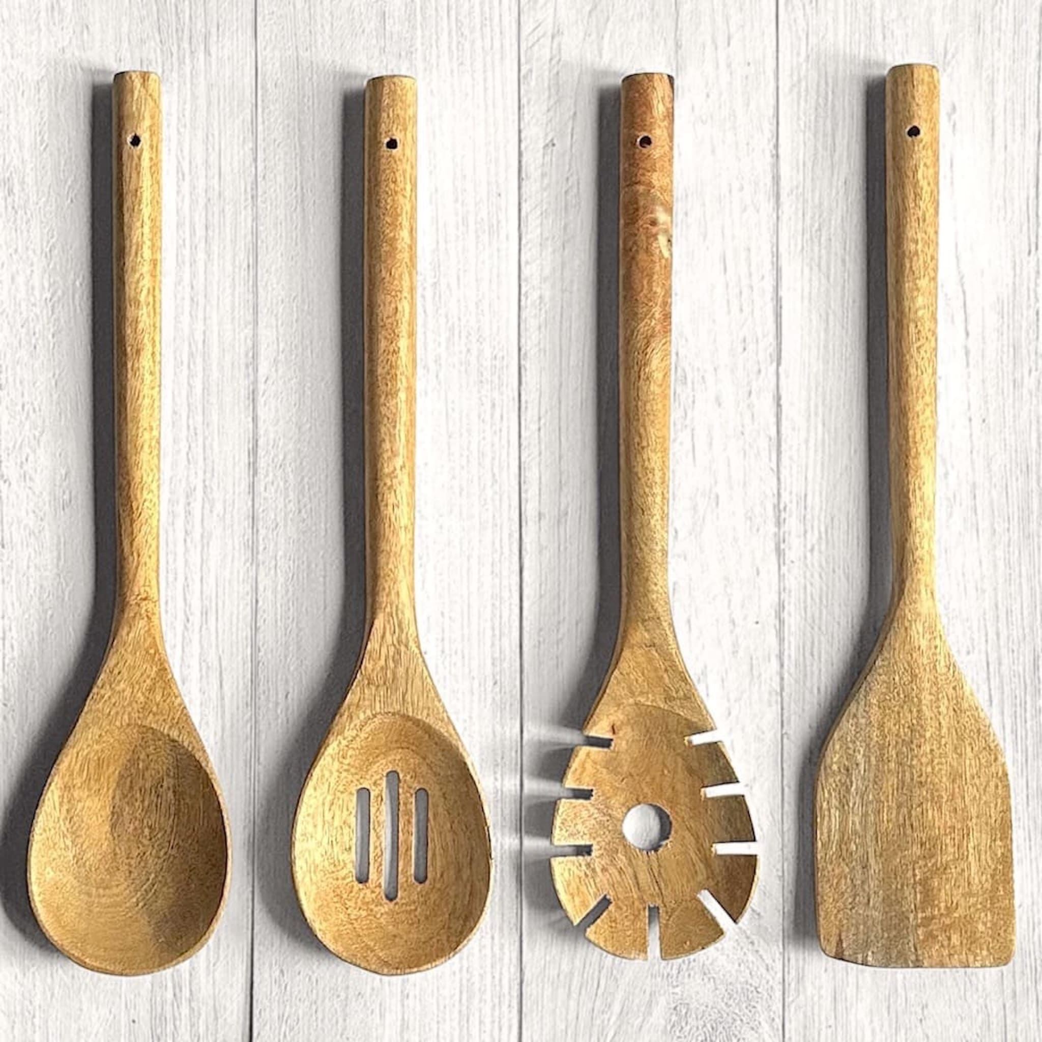 Set of four Mango wood kitchen utensils on a white wooden background