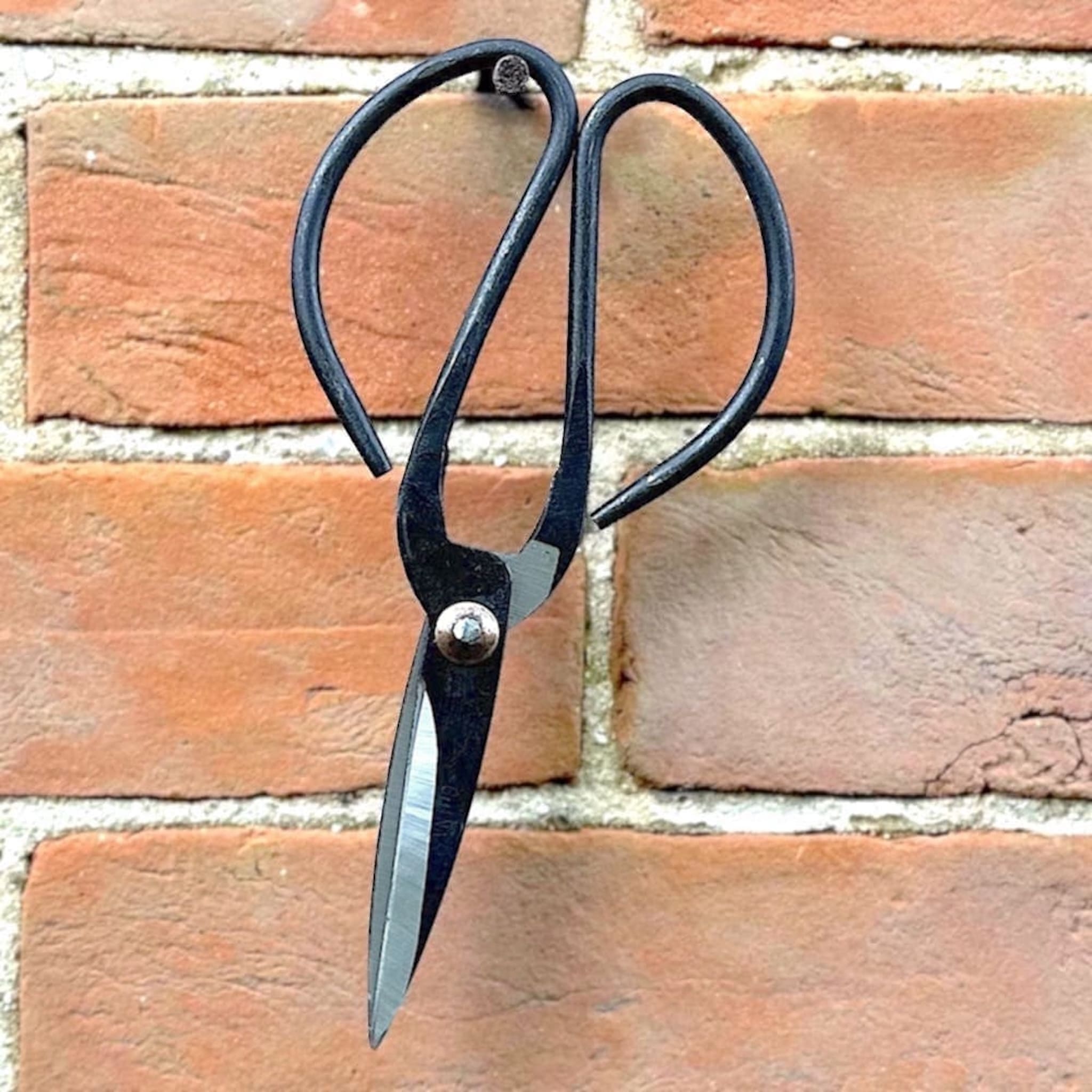 Black scissors hanging on a brick wall 