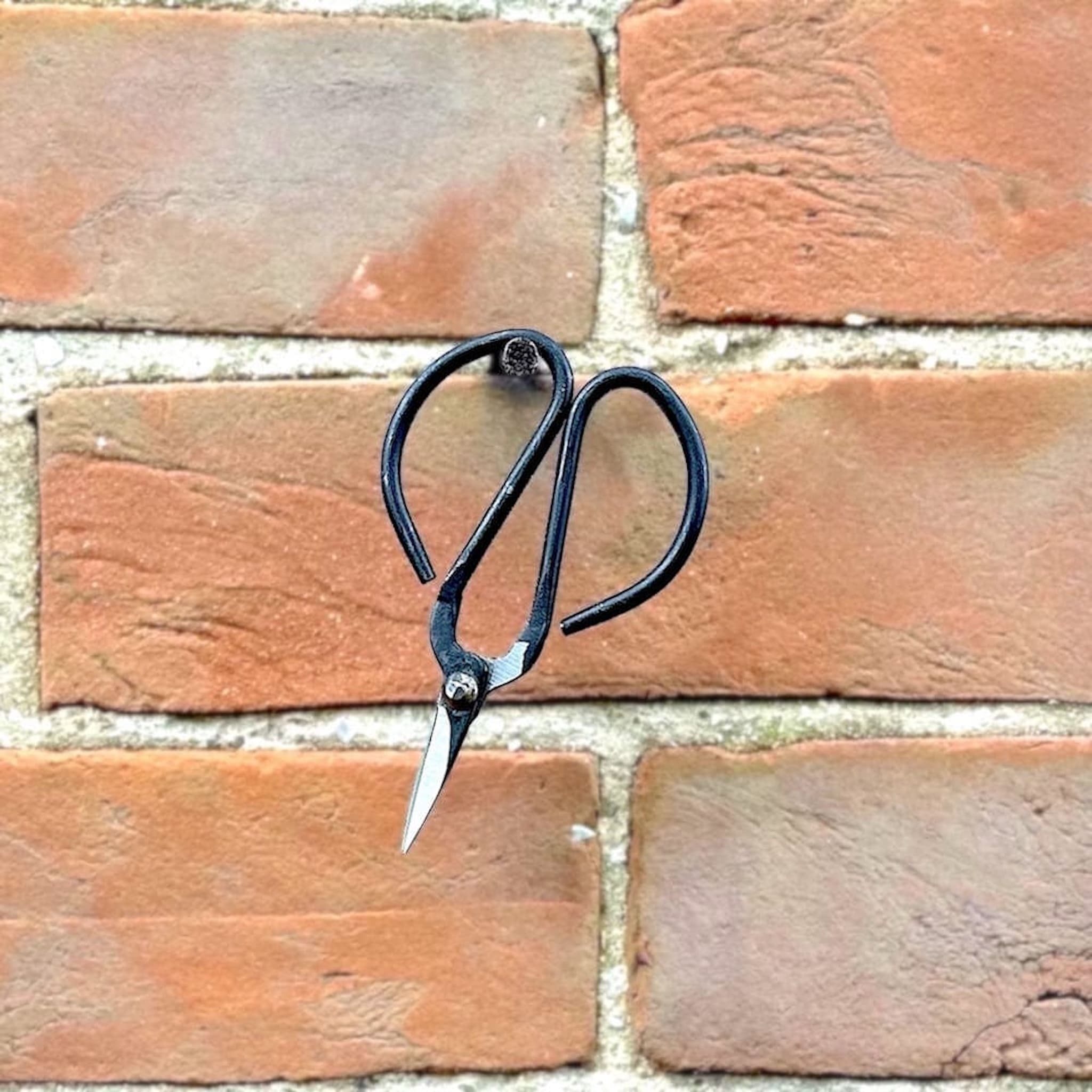 Black scissors hanging on a brick wall 