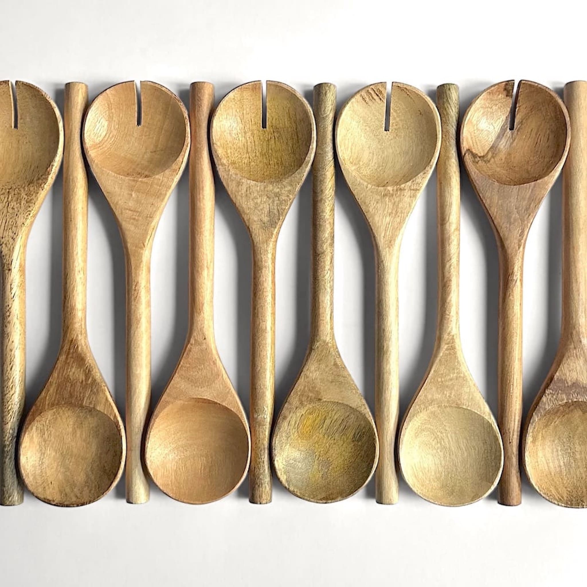 Row of mango wood serving spoons in varying colour and grain on a white background