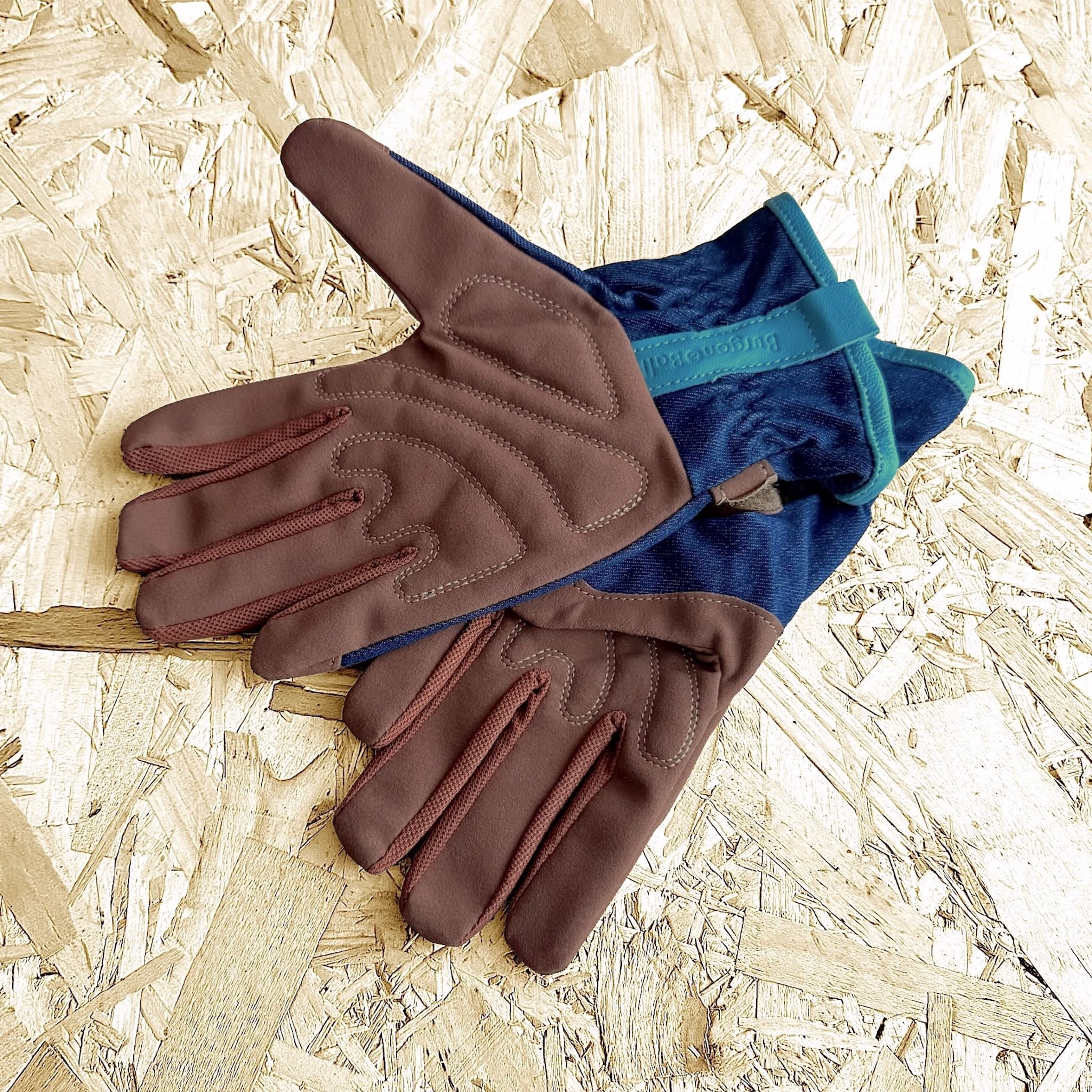 Pair of brown and blue gloves on a wooden surface